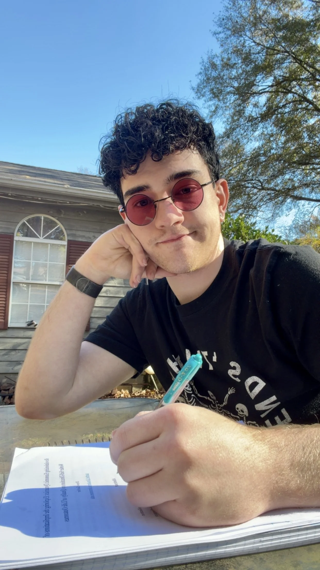 Drew smiling at an outdoor table in warm daylight.