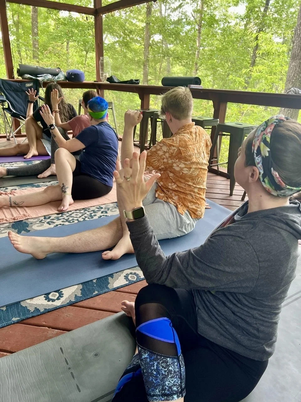 A small group seated together for yoga practice on a porch.