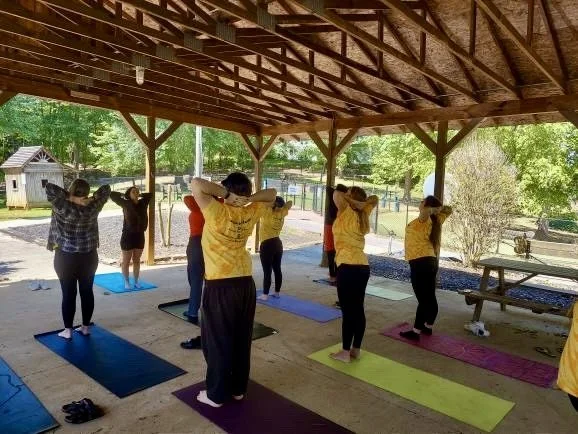 An outdoor group yoga class practicing together under a pavilion.