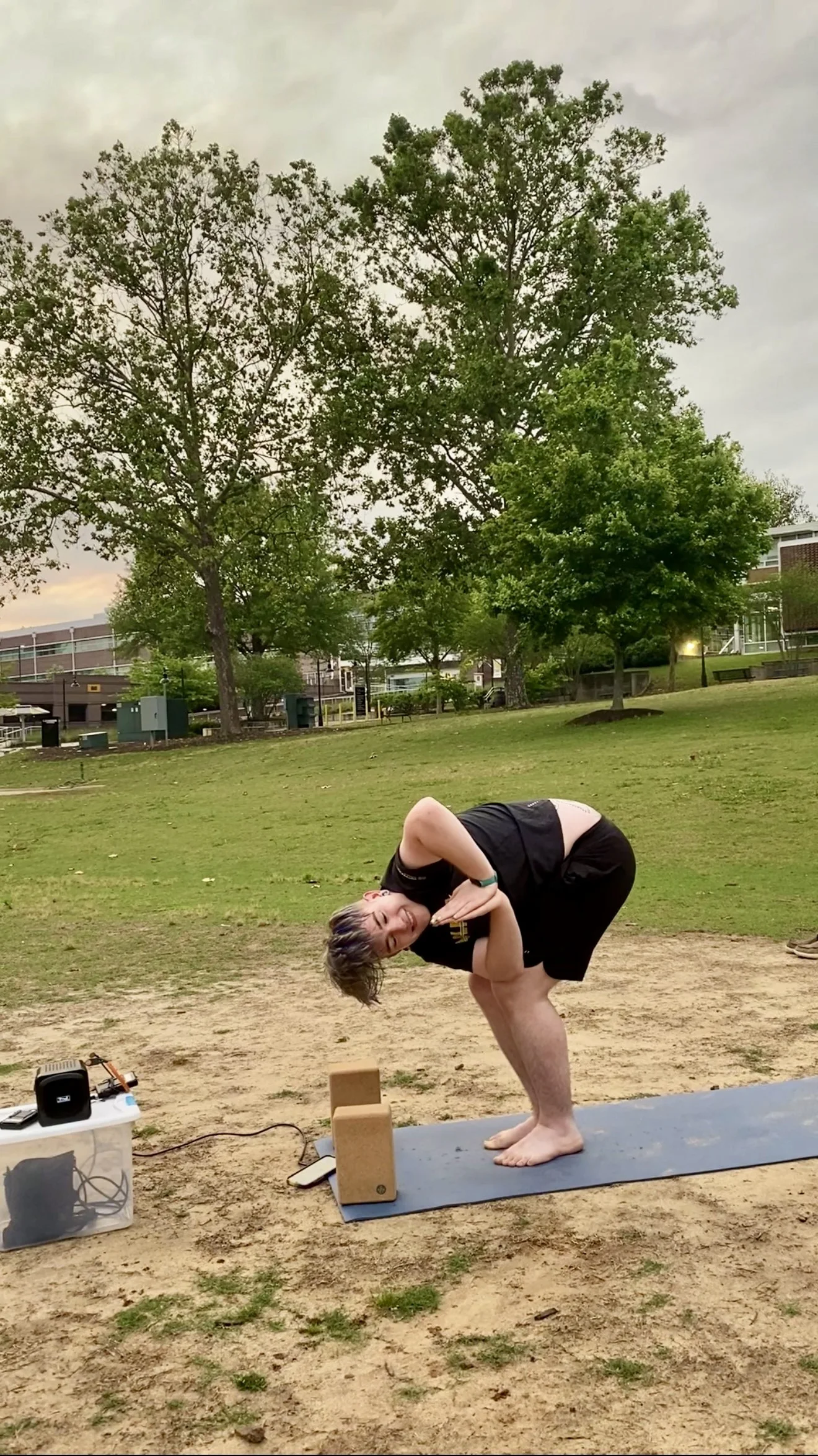 A student practicing a side bend outdoors on the grass.