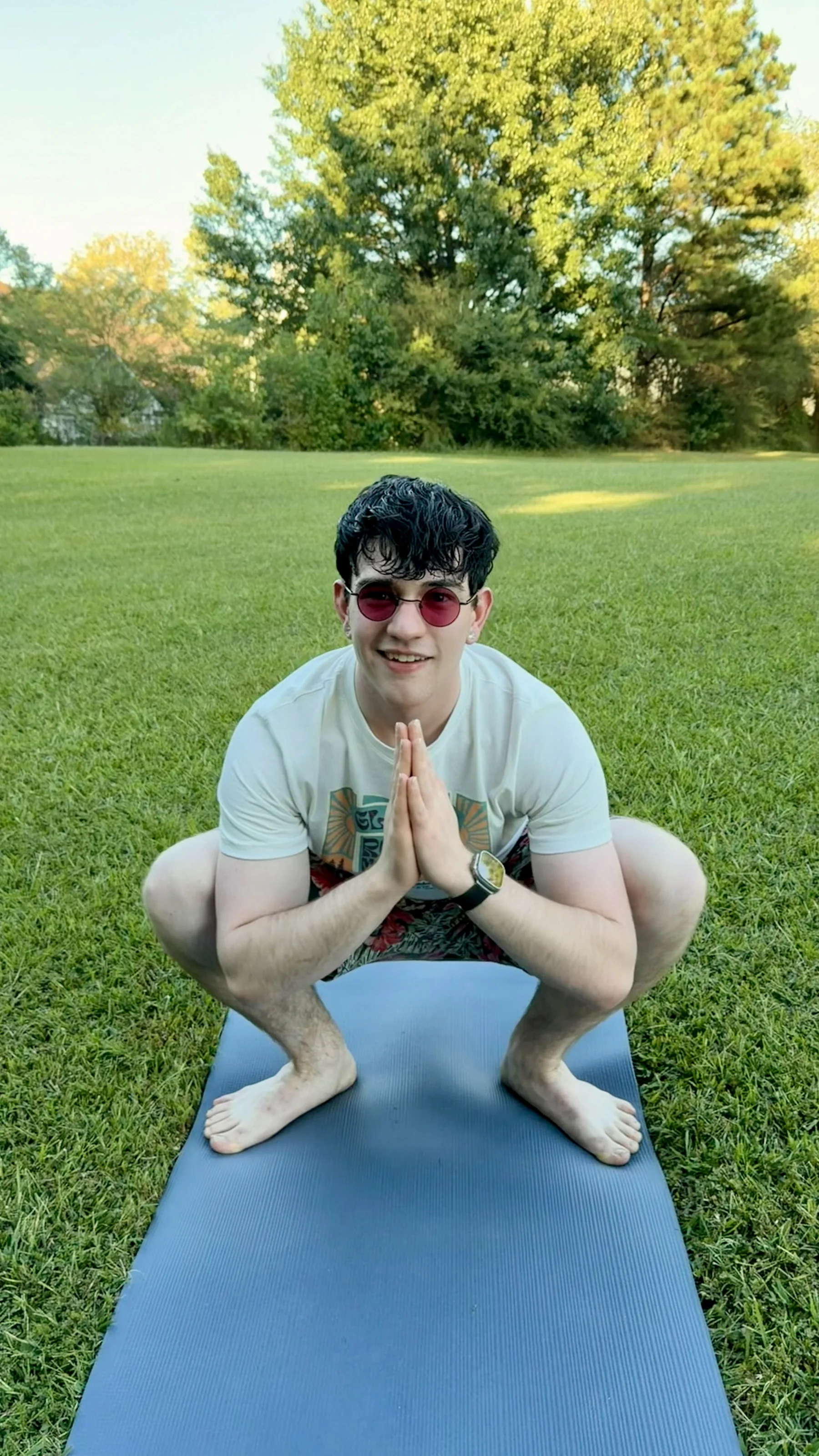 Drew crouched on a yoga mat in a welcoming outdoor practice space.
