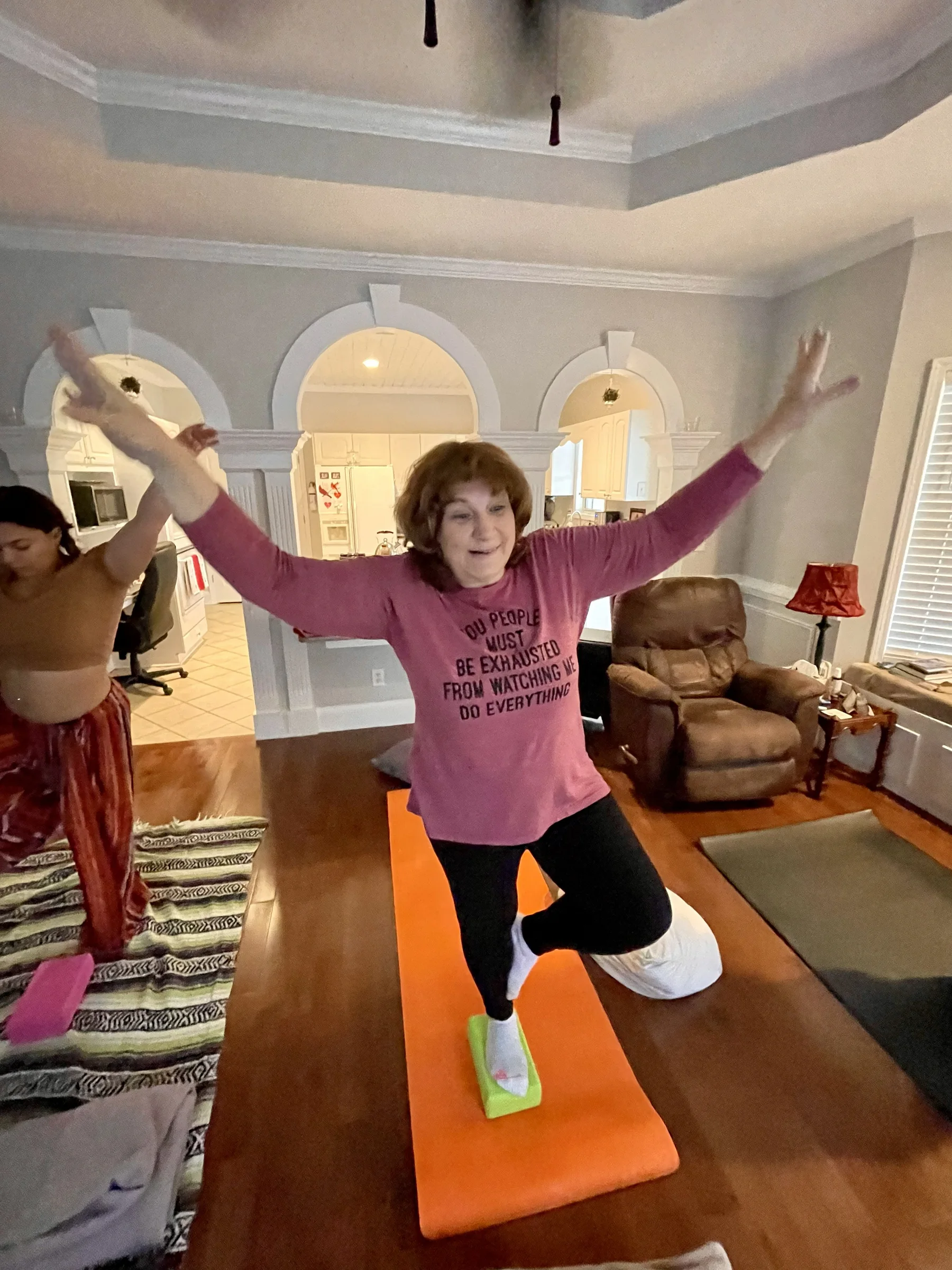 A student practicing a standing balance pose in a home yoga setting.