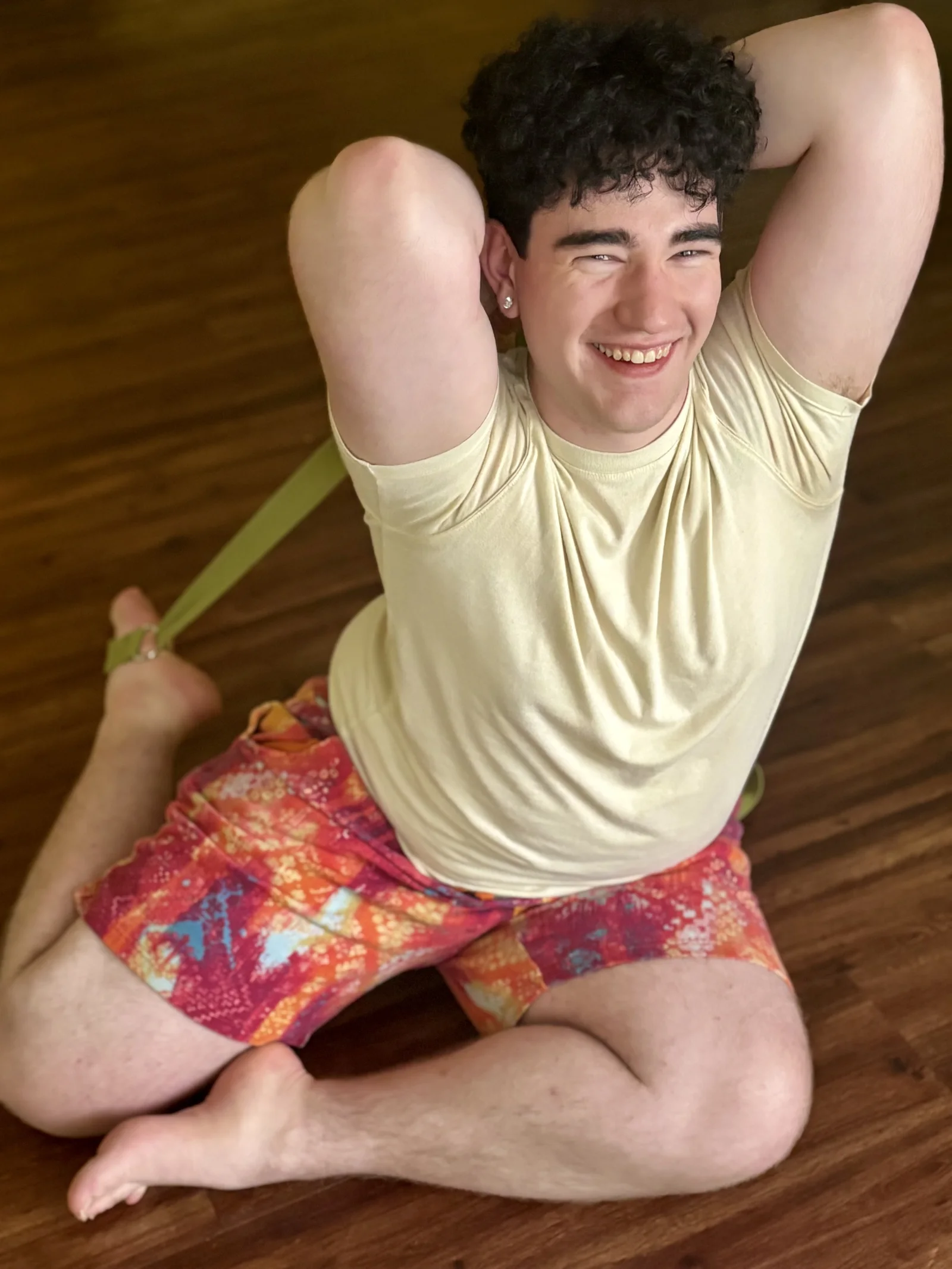 Drew smiling in mermaid pose with a yoga strap at Bee Humble Studio.