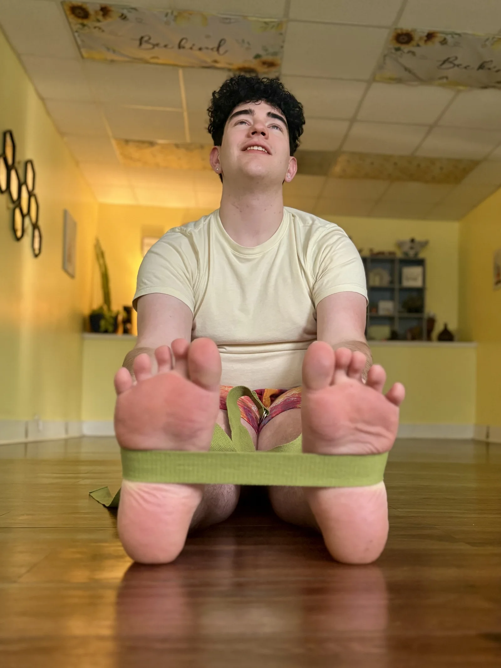 Drew practicing a seated stretch with a yoga strap at Bee Humble Studio.